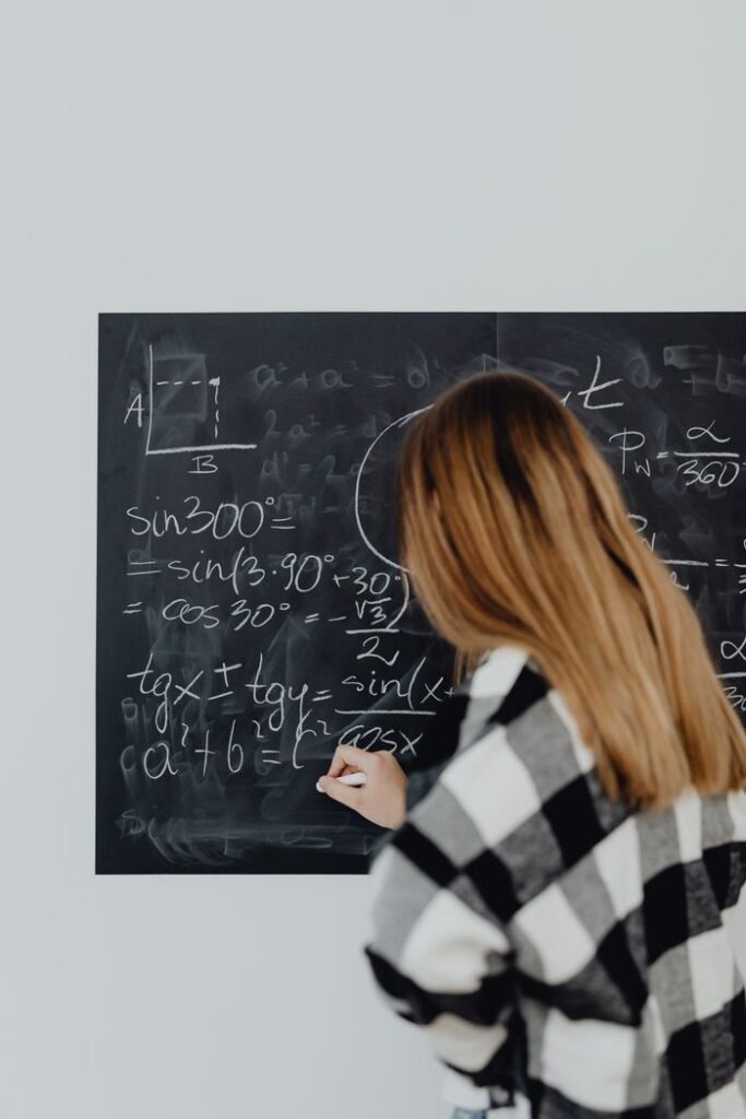 Kara tahtaya tebeşirle matematik formülleri yazan bir kadın